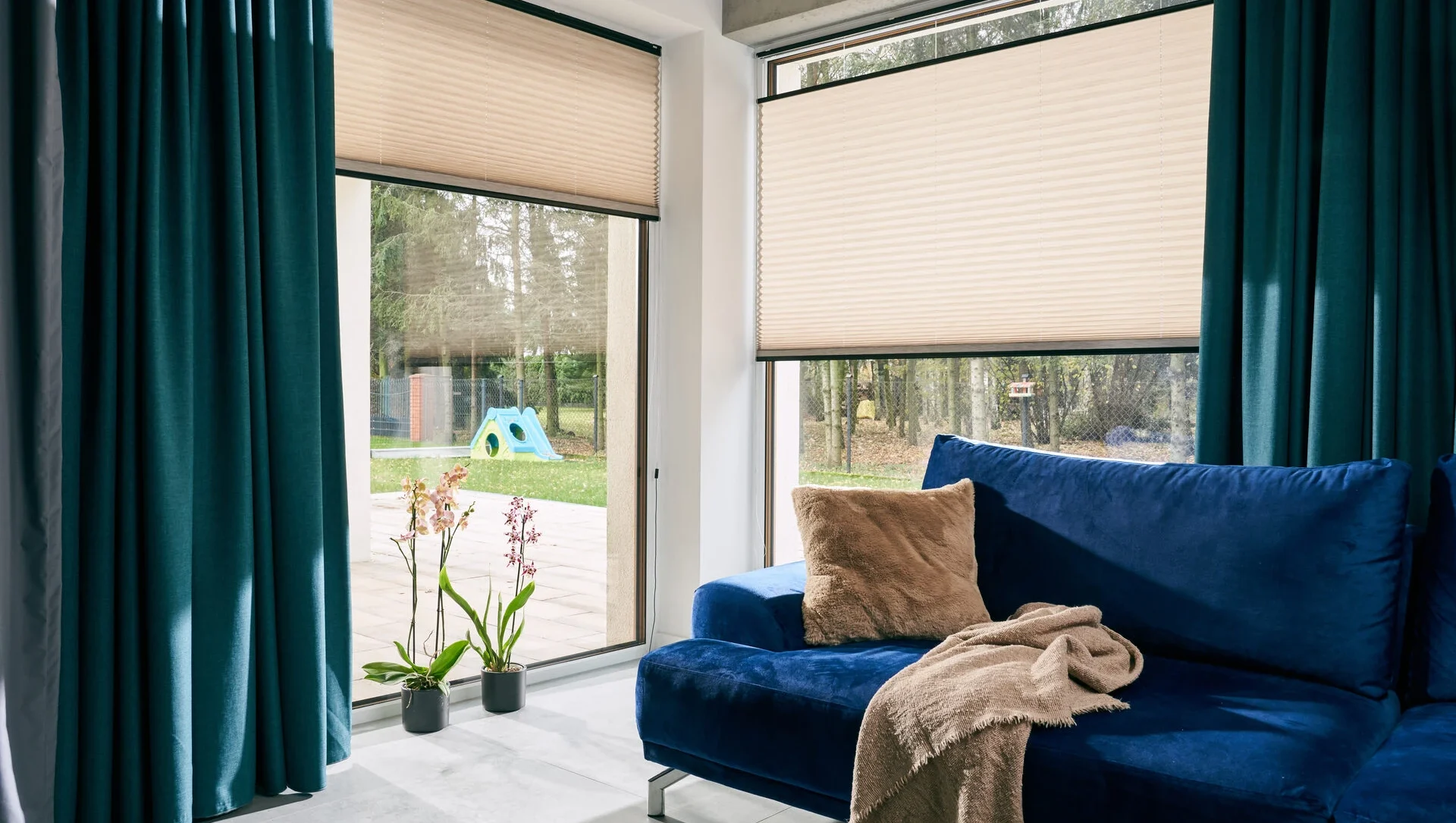 Modernes Wohnzimmer mit blauen Sofa und großen Fenstern